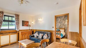 Ein gemütliches Zimmer mit einem Holzesstisch, einem Ledersofa und einem Holzkasten.