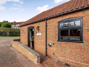 A brick building with a tiled roof, a sign reading "Viking Cottage," and a window with a metal grill. - Viking Cottage - UK36662 (Belchford)