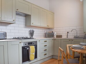 Eine Küche mit hellen Schränken, einem Toaster, einer Mikrowelle, einem Spülbecken und einem Holzespeisetisch.