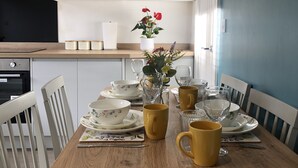 Une table à manger dressée avec des bols à motifs floraux, des tasses jaunes et de la verrerie transparente.