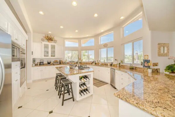 A spacious kitchen with white cabinets, a granite countertop, and a wine rack. - Beautiful Villa located in Temecula Wine Country (Temecula)