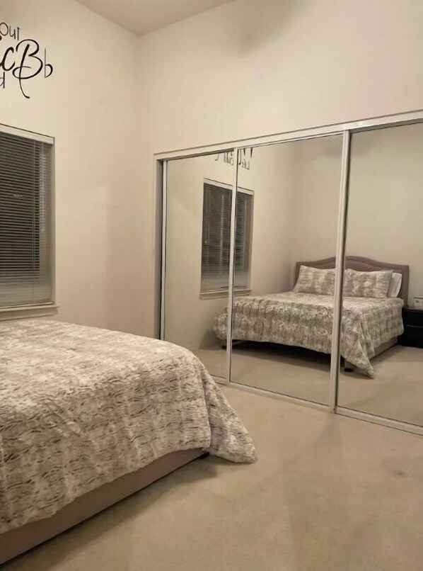 A bedroom with a bed, a mirror, and a sliding closet door.