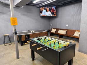 Une pièce équipée d’un baby-foot, d’un banc et d’un téléviseur fixé au mur.