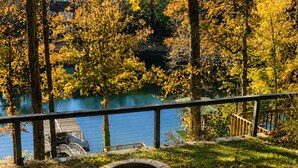 A lakeside outdoor area with a stone fire pit and a metal railing overlooking the water.