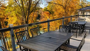 An outdoor patio with a table and chairs, surrounded by autumn foliage.