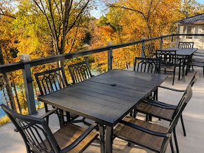 Un patio al aire libre con una mesa y sillas, rodeado de follaje otoñal.