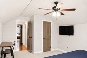 A room with a ceiling fan, a television mounted on the wall, and a dining area with a table and chairs. - The Gathering Place: Big Lakehouse/Covered Dock/Fiber/Tankless WH/Game RM/EV CHG (Cullman)