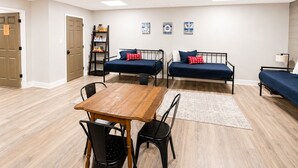 Una habitación con dos camas, una mesa de madera y sillas.