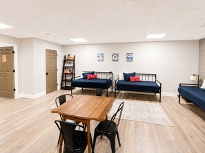 Una habitación con dos camas, una mesa de madera y sillas.