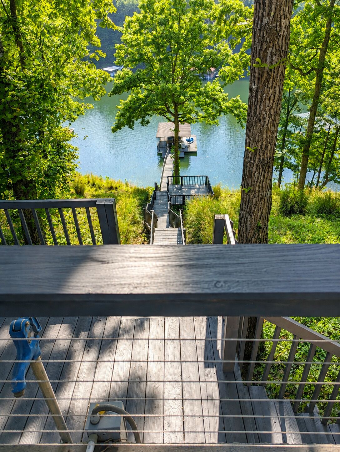 A wooden deck with a view of a lake and dock.