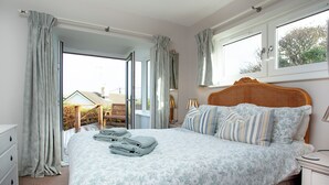Un dormitorio con cama, mesita de noche, cómoda y ventana con cortinas.
