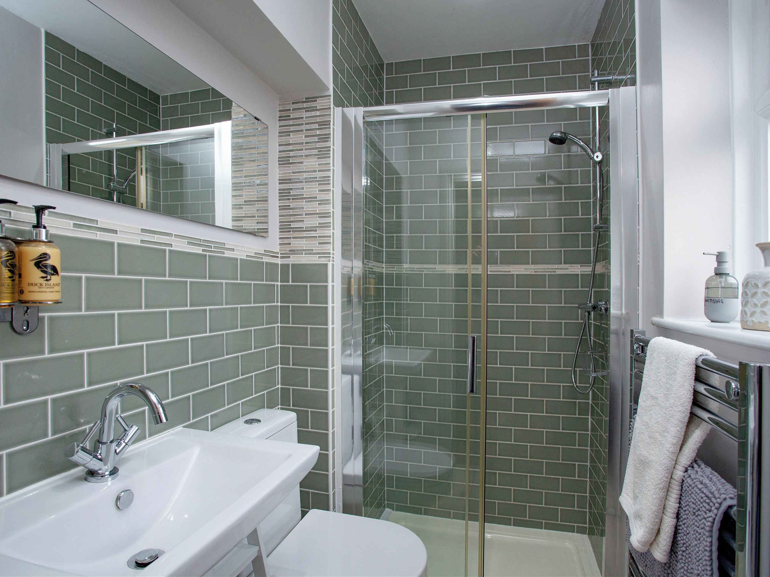 A modern bathroom with a glass-enclosed shower, a sink, and a toilet.