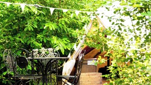 Une terrasse extérieure avec une table et des chaises en métal, entourée de verdure.