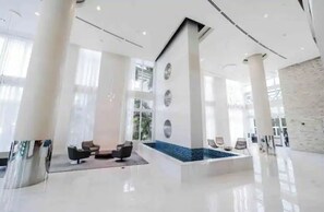 Relax in the elegant lobby, featuring a central seating area, water feature, and sleek pillars.
