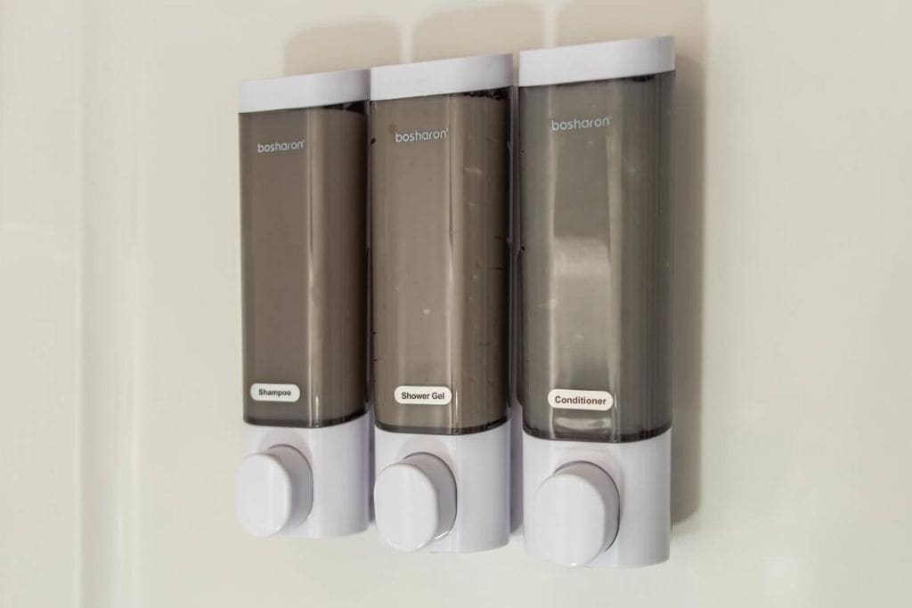 Three wall-mounted dispensers labeled 'shampoo,' 'shower gel,' and 'conditioner.'