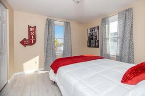 A bedroom with a bed, a window with curtains, and an exit sign on the wall. - Historic District, Downtown, STE 4 (Rapid City)