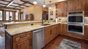 A modern kitchen with wooden cabinets, stainless steel appliances, and pendant lighting.