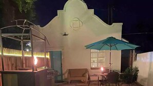 Un jardin avec un foyer extérieur, un espace patio doté d’une table et de chaises, et un coin salon abrité.