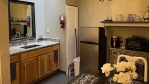 Une cuisine compacte avec des meubles en bois, un réfrigérateur en acier inoxydable, un four à micro-ondes et un lustre.