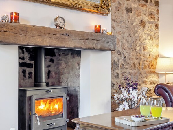 A cozy room with a wood-burning stove, a clock, and a table with drinks and a tray.