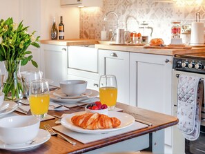 A breakfast setting with croissants, fruit, and orange juice on a wooden table. - 3 bedroom accommodation in Wooler (Wooler)