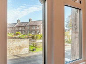 A view of Burnhouse Road with a stone wall and a multi-story building with a grey roof. - 3 bedroom accommodation in Wooler (Wooler)