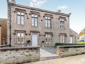 A stone building with a white door, multiple windows, and a small garden area in front. - 3 bedroom accommodation in Wooler (Wooler)