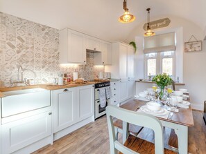 A kitchen with white cabinets, a wooden countertop, a stove, and a dining table set for four.