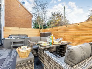 A backyard with a hot tub, outdoor seating, and a barbecue grill.