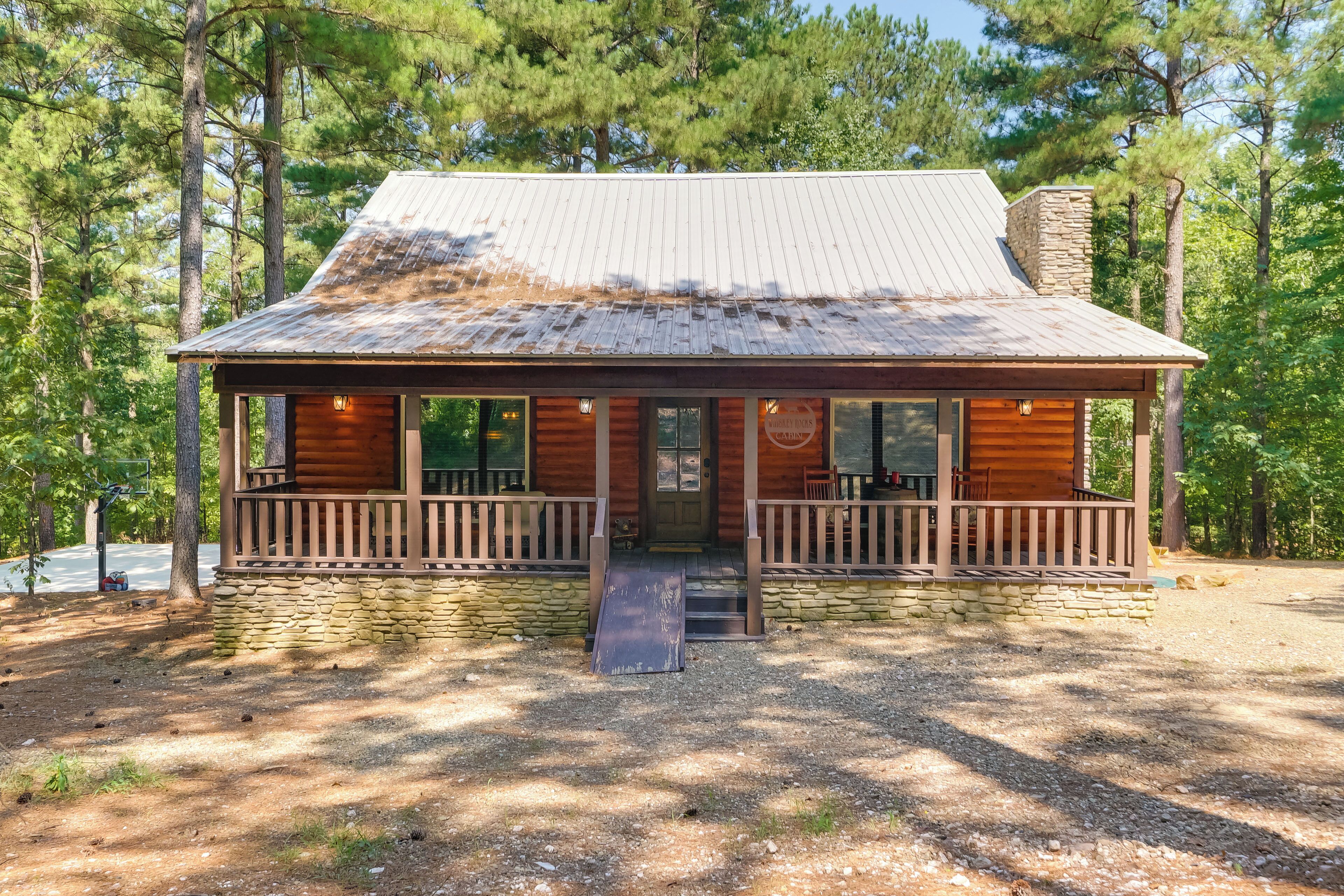 A rustic cabin with a metal roof, wooden exterior, and a porch with seating.