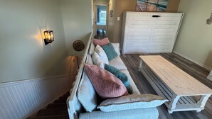 Un couloir avec un banc, un luminaire fixé au mur et un grand meuble.