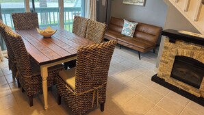 Un coin repas avec des chaises en osier, une table en bois et une cheminée.