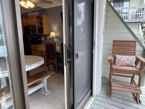 A sliding glass door leading to a kitchen with wooden cabinets and a dining area with a table and chairs. - Paradise PRN (gulf shores)
