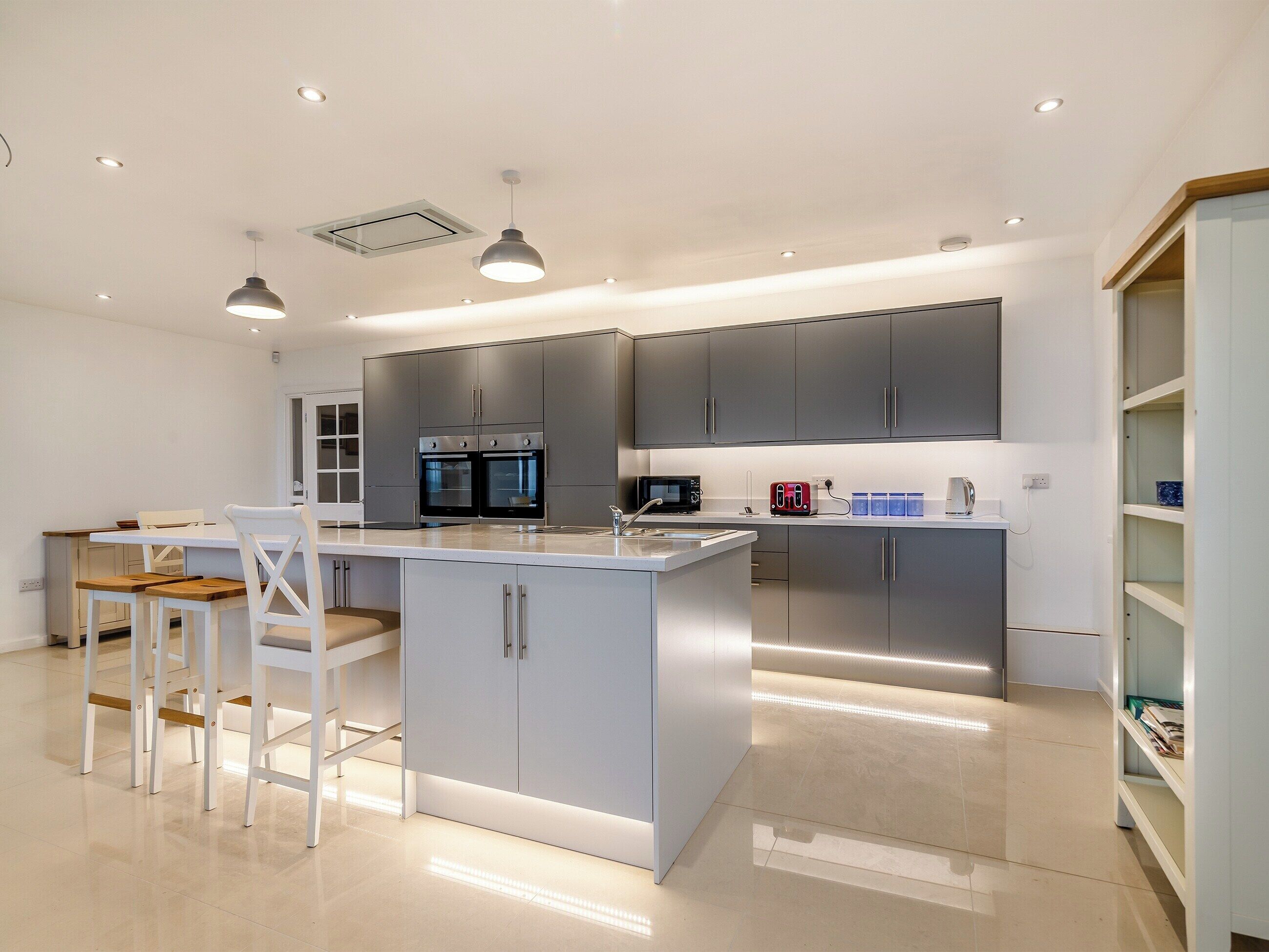 A modern kitchen with grey cabinets, a central island, and pendant lighting.