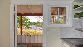 Une cuisine avec vue sur un lac, une terrasse en bois et une fenêtre donnant sur les arbres.