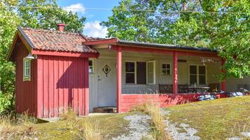 Un bâtiment en bois rouge, doté d’un porche et d’une petite remise attenante.