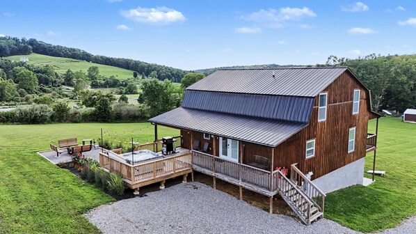 A wooden cabin with a deck, a hot tub, and a view of the surrounding countryside. - Ridge top cabin with hot tub and movie theater (Logan)