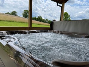 Un jacuzzi con vista a un campo cubierto de césped y árboles.