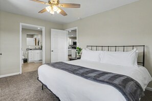 A bedroom with a bed, a ceiling fan, a bathroom with a toilet and sink, and a kitchenette with cabinets and a microwave. - Ridge top cabin with hot tub and movie theater (Logan)