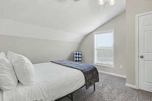 A bedroom with a bed, a window with blinds, a door, and a ceiling light fixture. - Ridge top cabin with hot tub and movie theater (Logan)