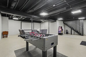 A room with a foosball table, a sofa, a small table, and a trash bin. - Ridge top cabin with hot tub and movie theater (Logan)