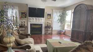 Una sala de estar con chimenea, televisión y un mueble de madera grande.