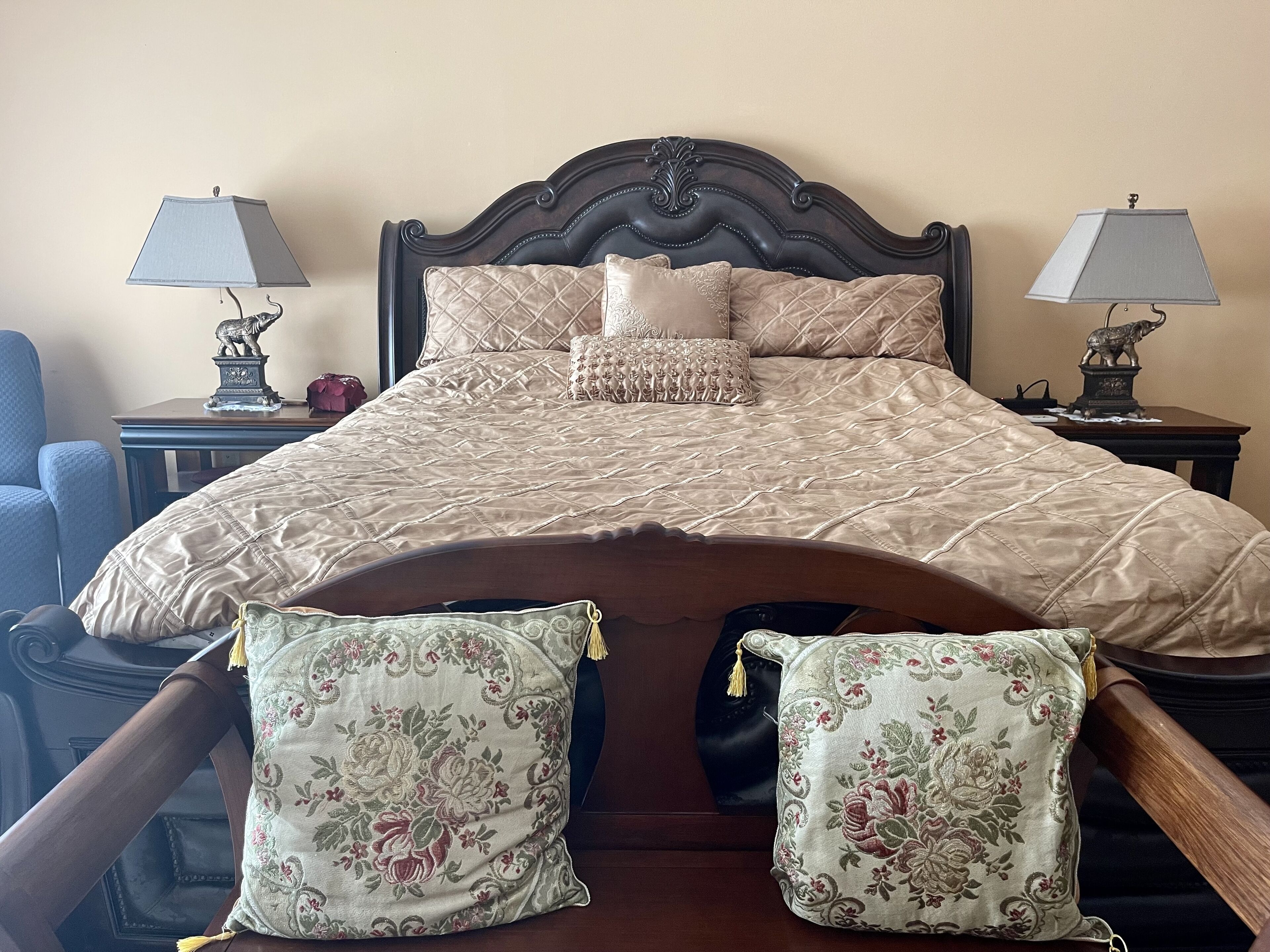 A bed with a dark wooden headboard, two matching nightstands, and floral-patterned pillows.