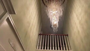 Un candelabro cuelga del techo en una habitación con un ventanal de barrotes y un adorno en la pared.