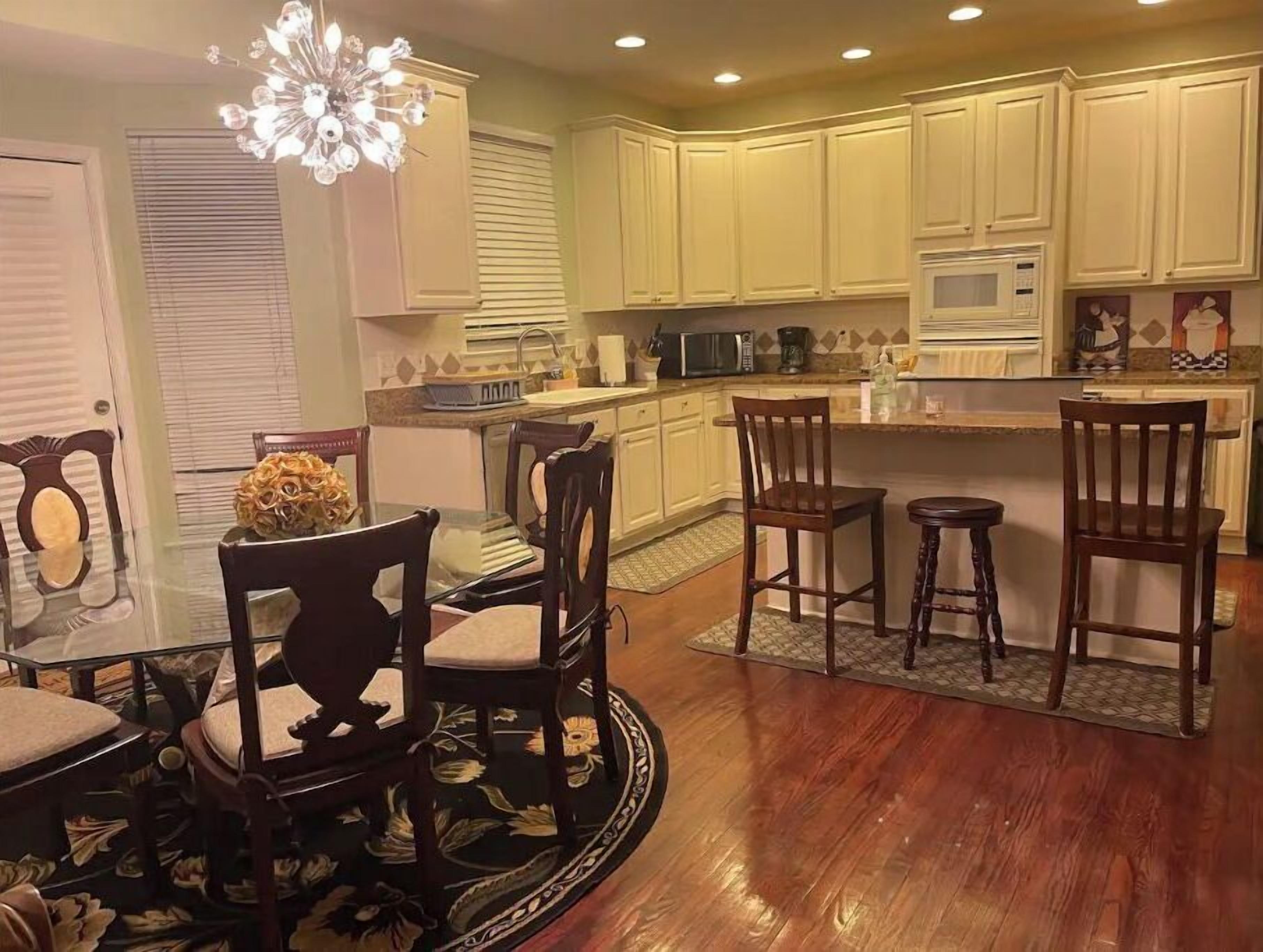 A kitchen with white cabinets, a dining area with wooden chairs, and a central island.