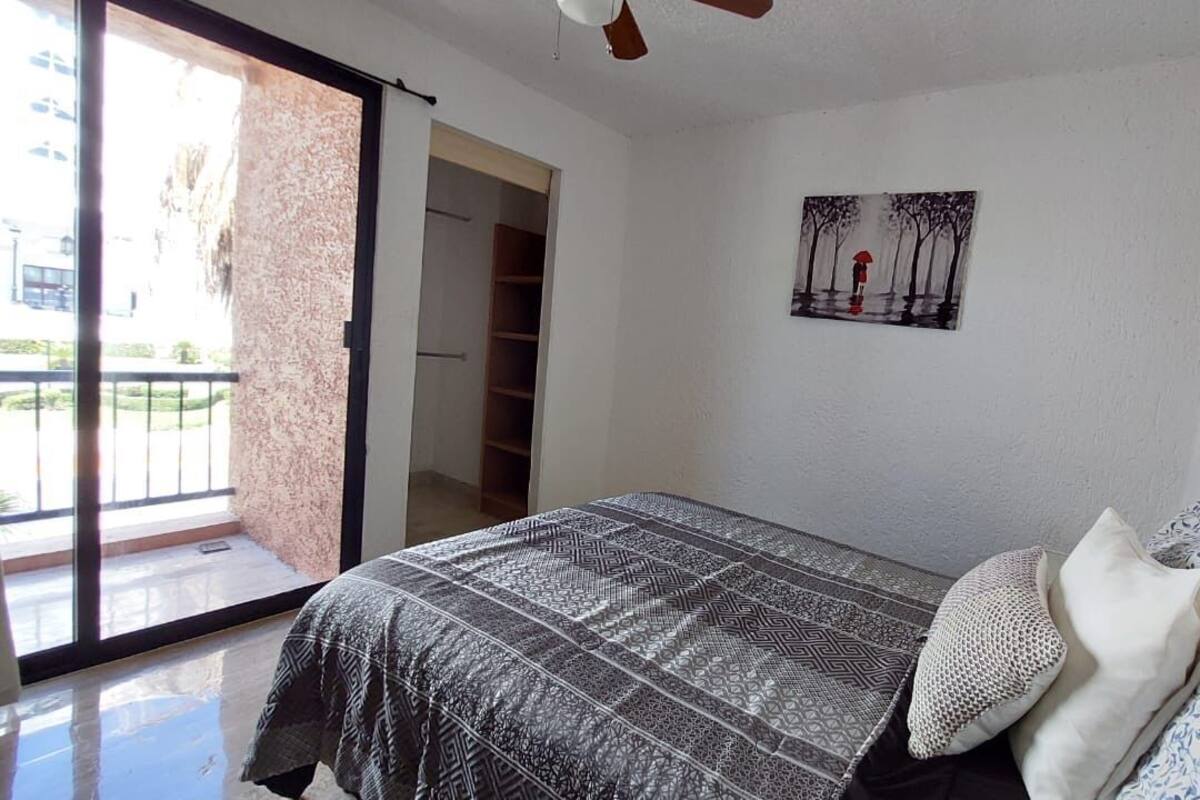 A bedroom with a bed, a painting, and a sliding glass door to a balcony.