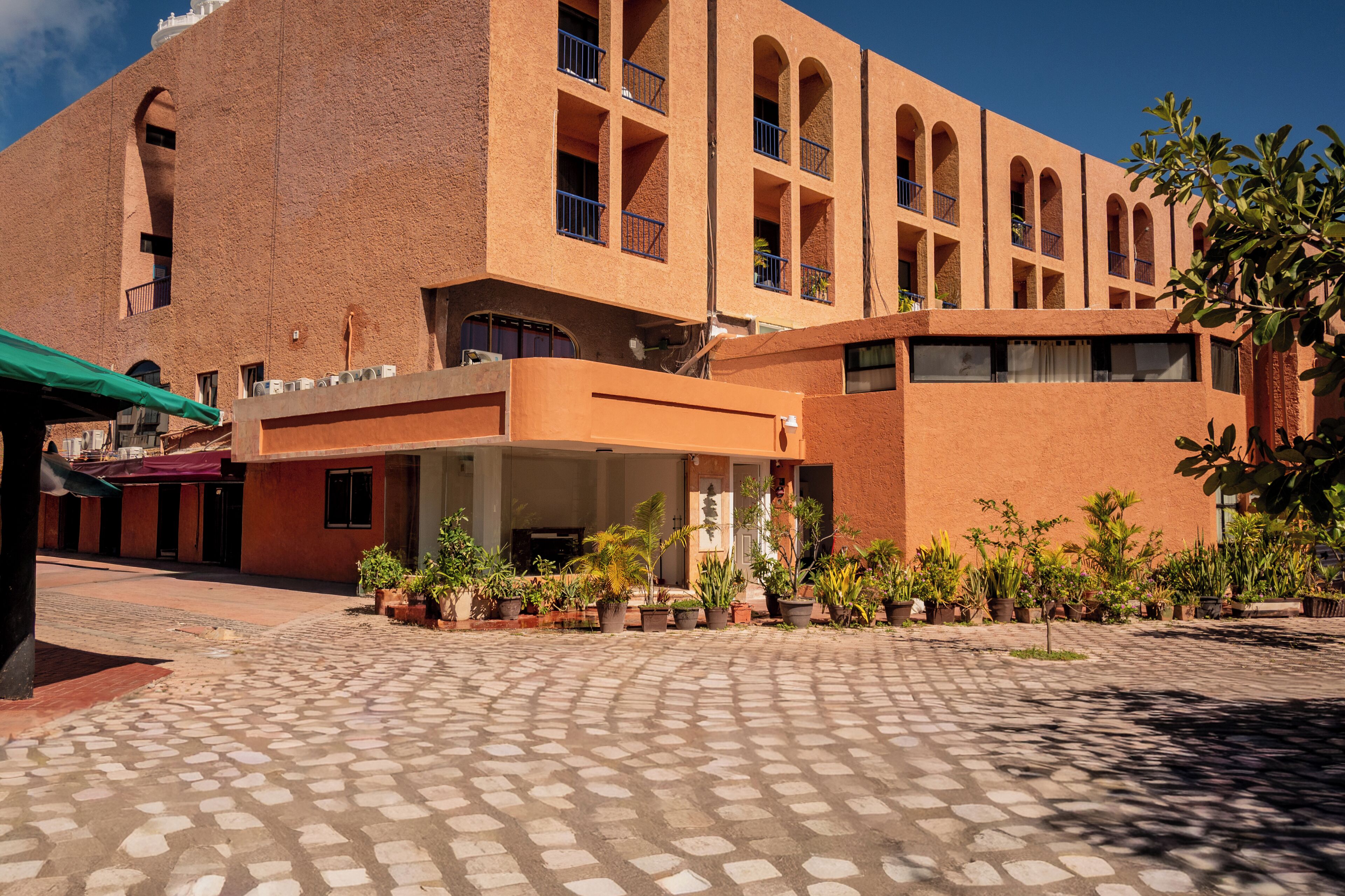 A building with a courtyard, potted plants, and a covered entrance.