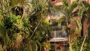 A pathway flanked by lush greenery and a building with multiple balconies. - CANCUN SUITES APARTMENTS - HOTEL ZONE (Cancun)