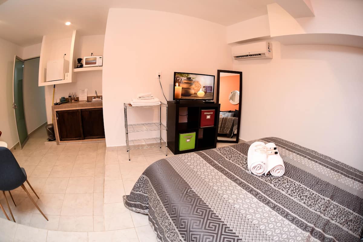 A hotel room with a bed, a desk with a computer, a microwave, and a TV.