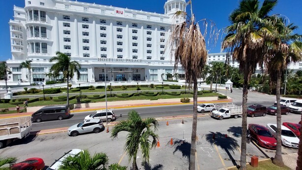 A large, white hotel with a classic architectural style, featuring a prominent entrance and a well-maintained garden area. - CANCUN SUITES APARTMENTS - HOTEL ZONE (Cancun)